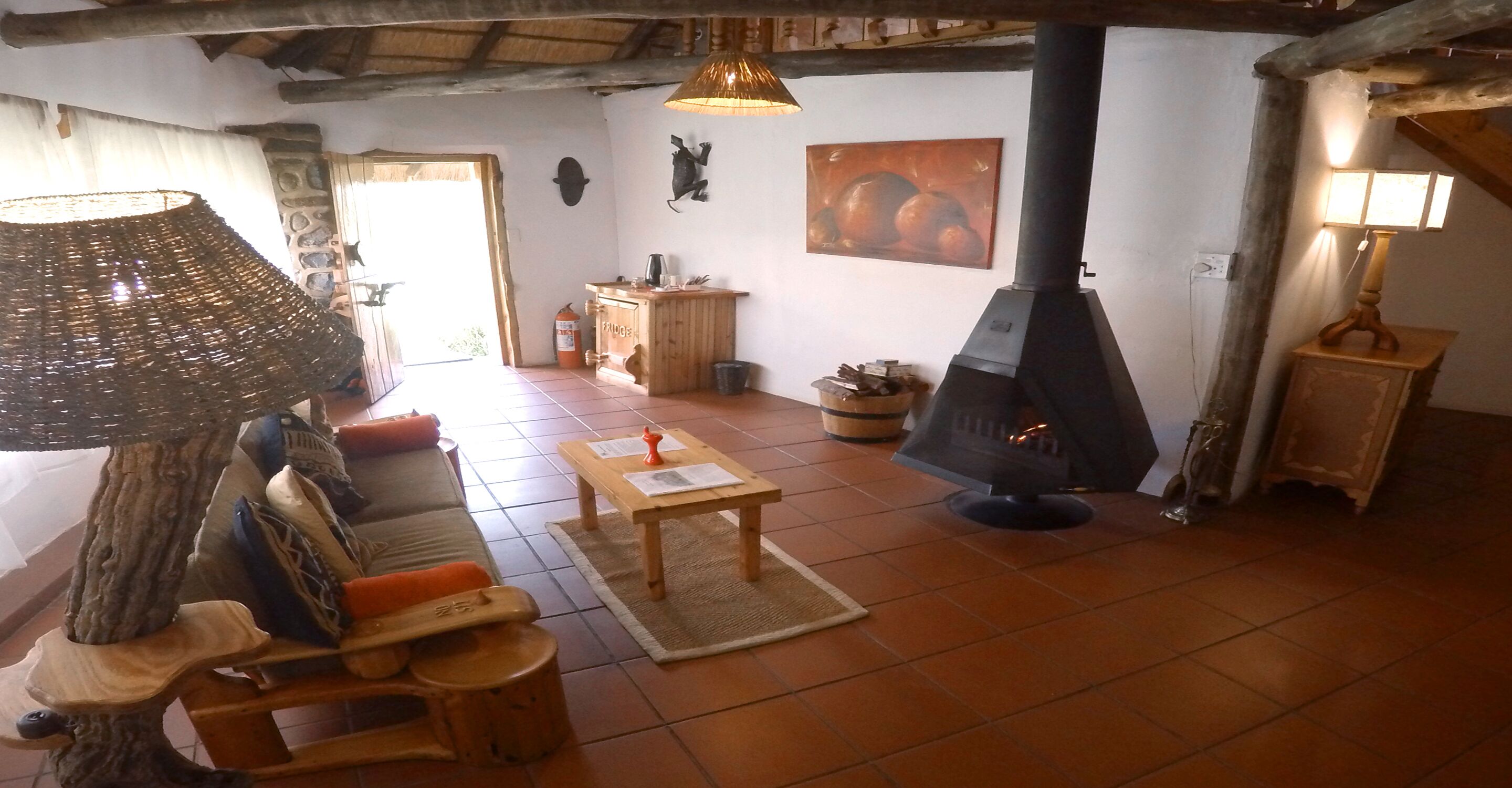 A cozy living room with a fireplace, wooden furniture, and a rustic ceiling.
