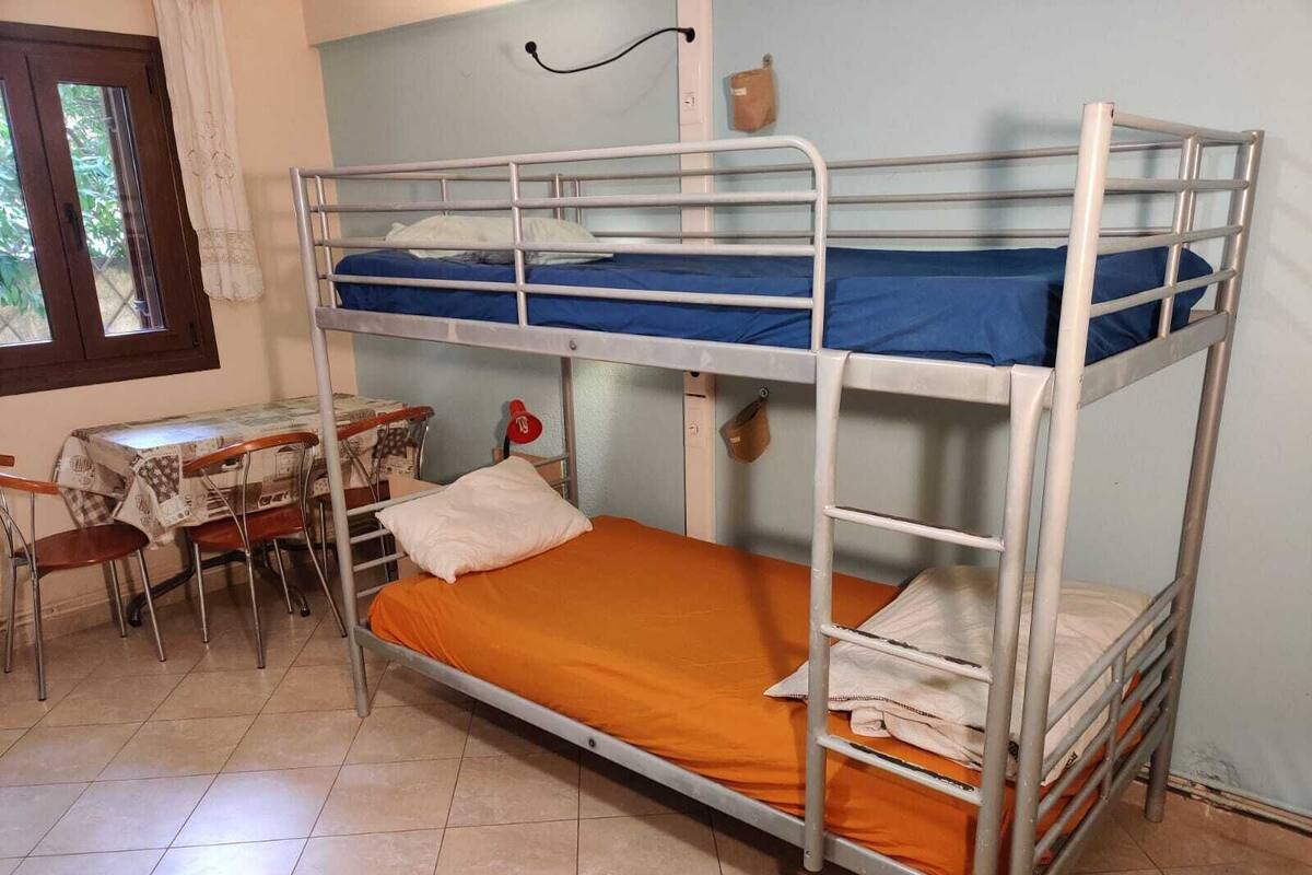 A bunk bed room with a desk and chairs.