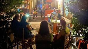 An outdoor seating area with tables and chairs, surrounded by buildings and trees. - Arabas - Hostel (Thessaloniki)