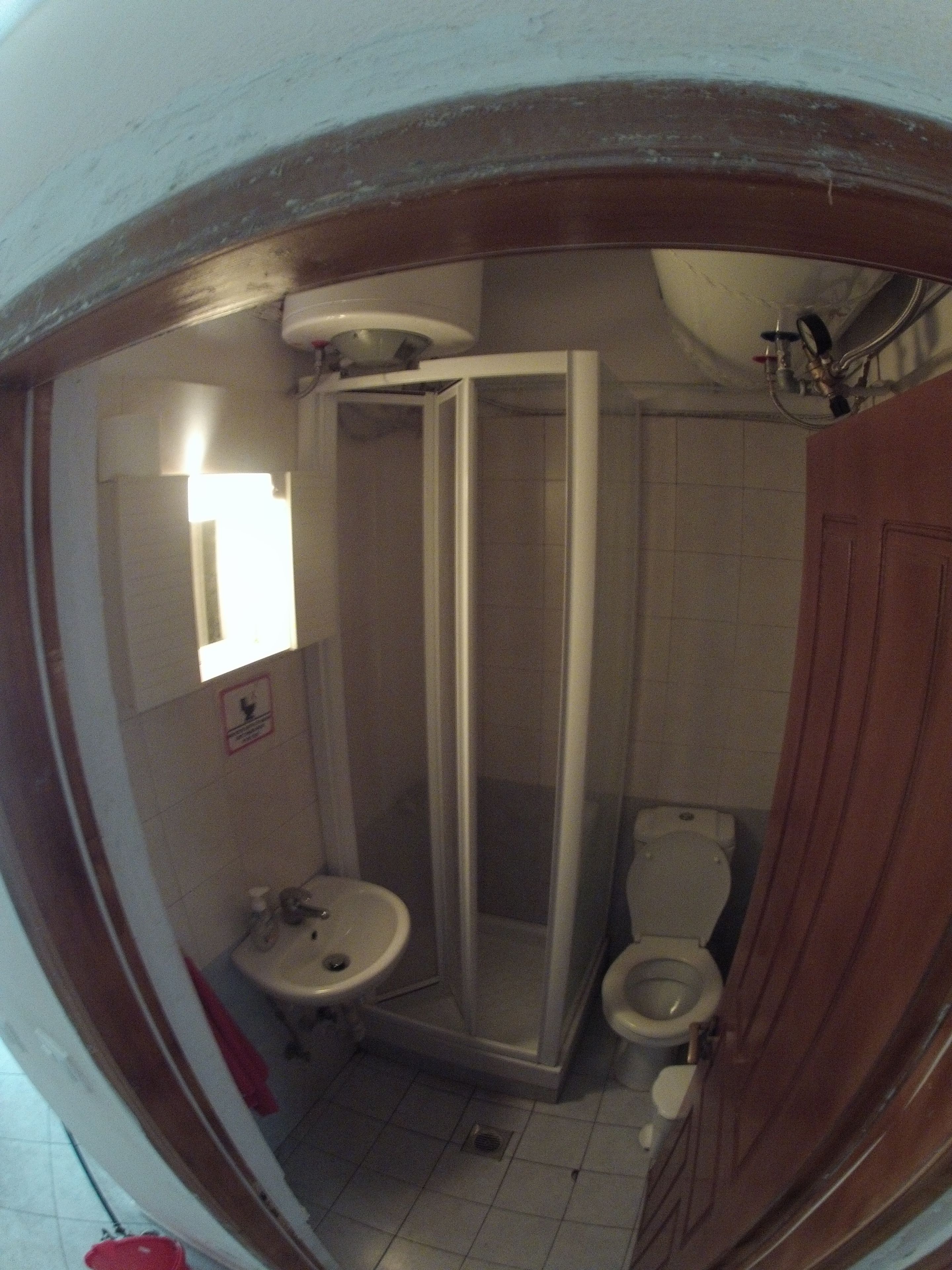 Een badkamer met douche, toilet, wastafel en spiegel.