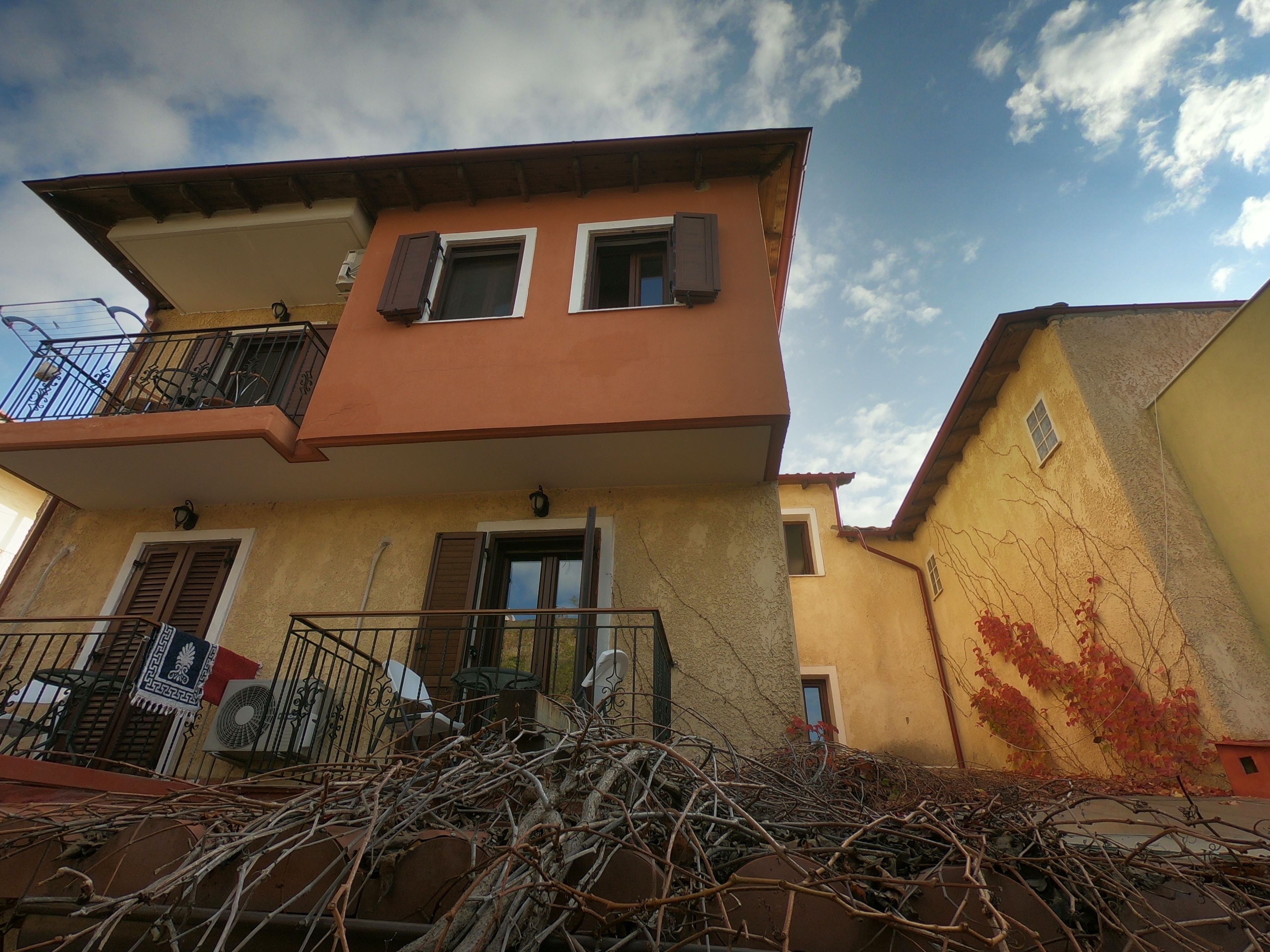 A two-story building with a balcony, a door, and a window.
