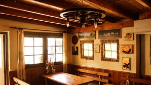 A rustic interior with wooden beams, a wooden table with benches, and artwork on the walls. - Arabas - Hostel (Thessaloniki)