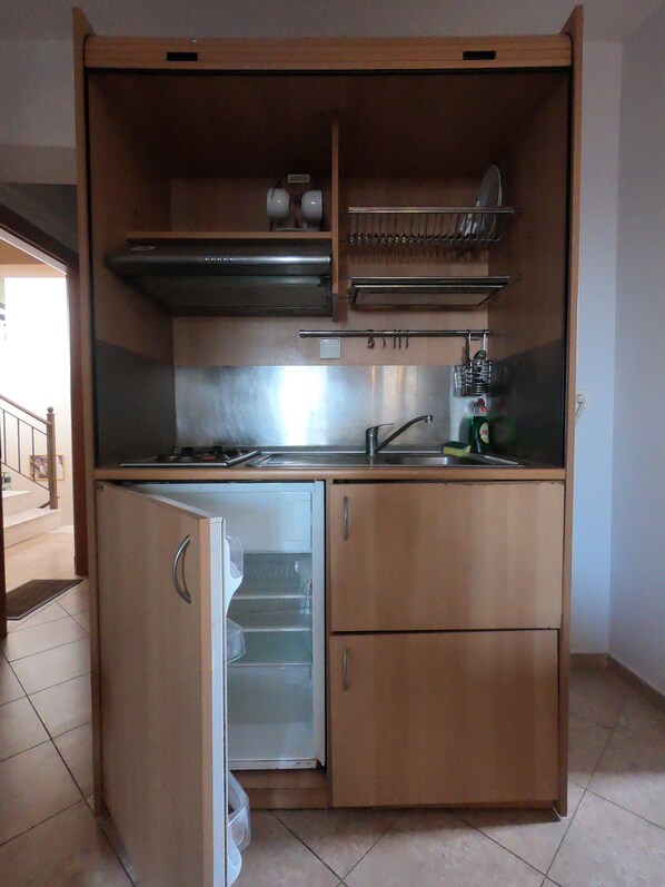 Una cocina compacta con refrigerador, estufa y lavaplatos.
