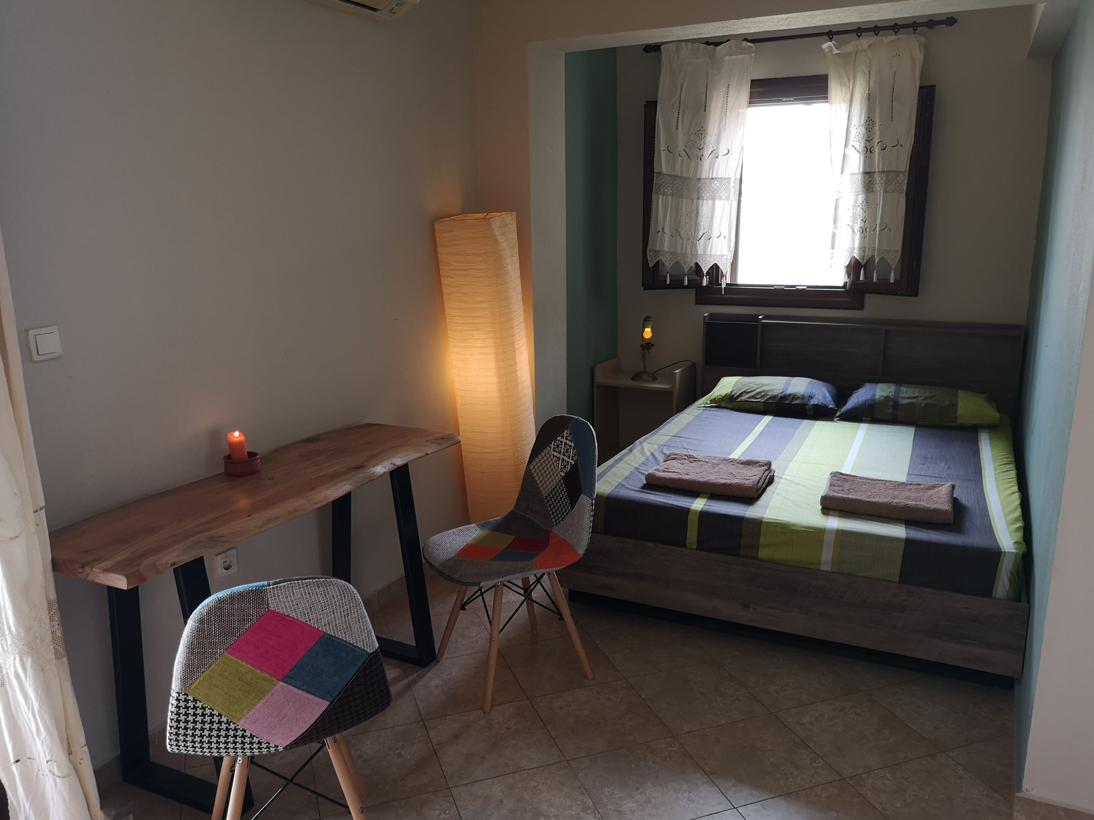 Une chambre à coucher comprenant un lit, un bureau, une chaise, une table de chevet et une lampe.