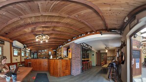 A wooden interior with a bar area, seating, and a bicycle. - Arabas - Hostel (Thessaloniki)