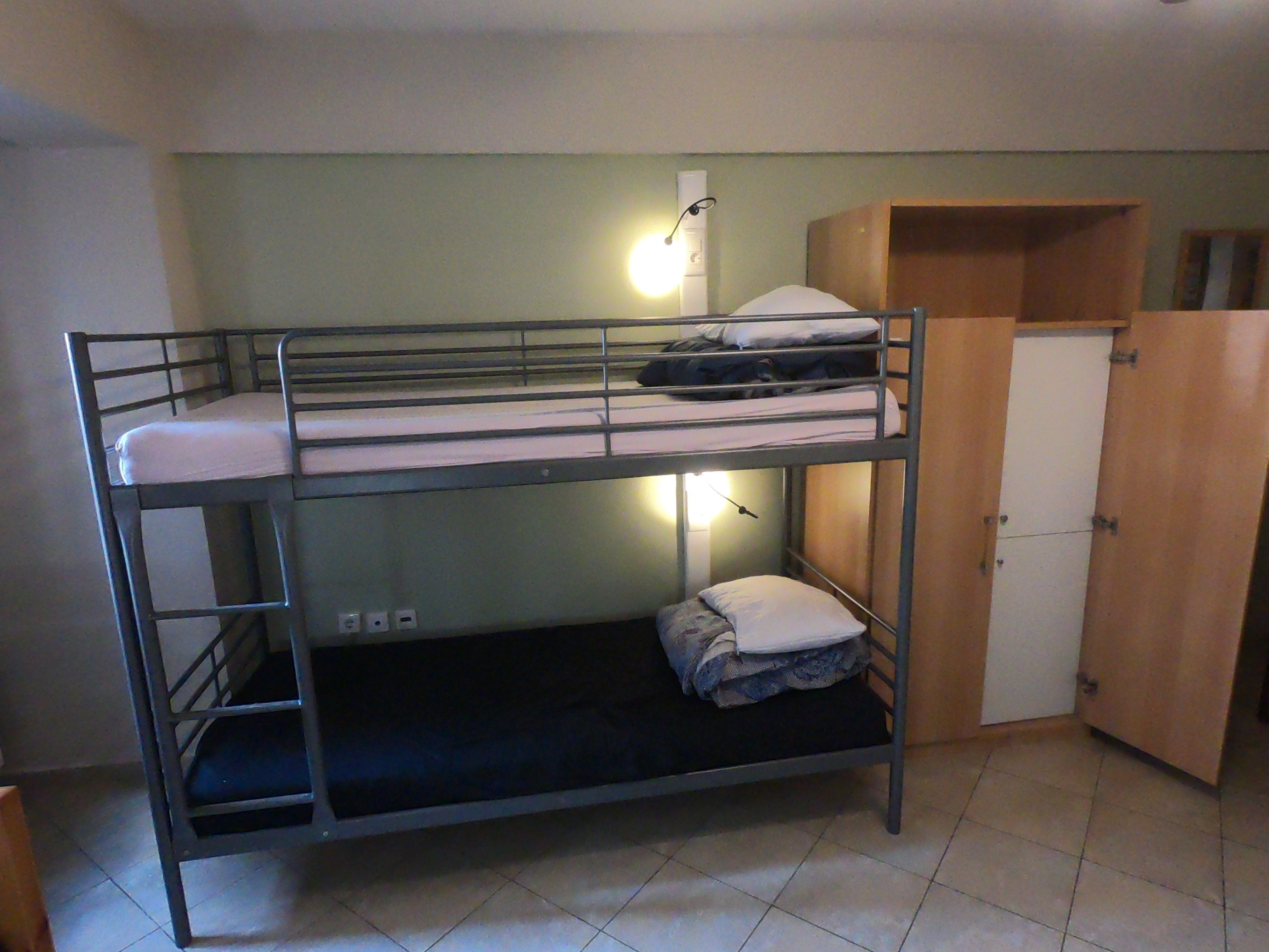 Ein Etagenbett mit Schreibtisch und Kleiderschrank in einem kleinen Zimmer.