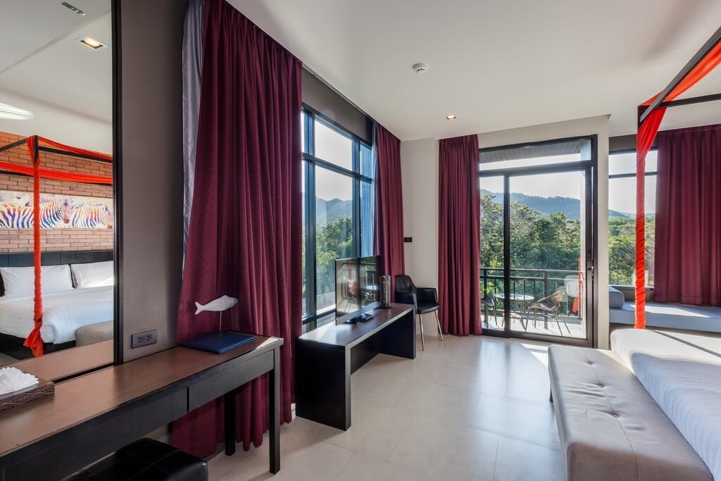 Una moderna camera d'albergo con un letto grande, una scrivania e un balcone che offre vista sulle montagne.