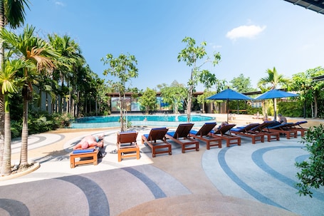 Una piscina al aire libre, sillones reclinables de piscina