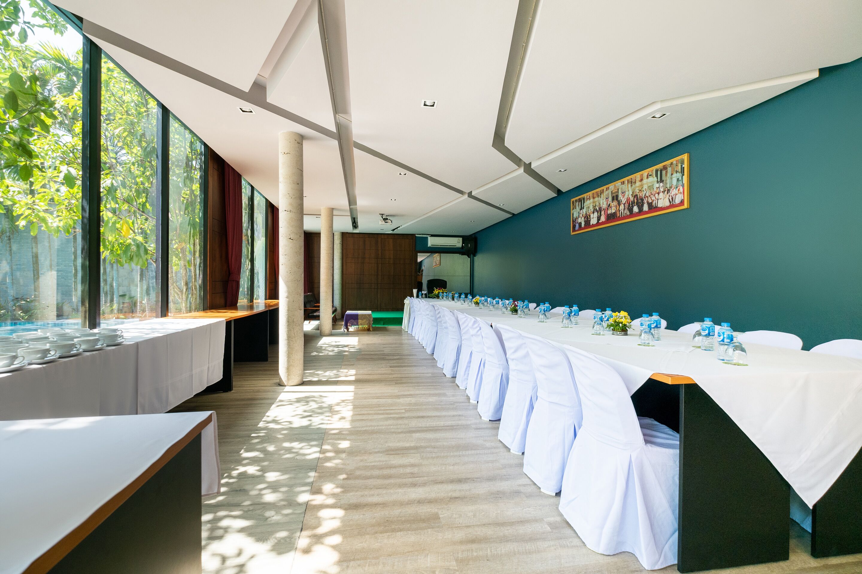 A conference room with long tables, white tablecloths, and water bottles.