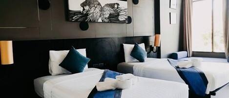 Habitación de hotel con dos camas, un cuadro abstracto grande en la pared y una ventana con cortinas.