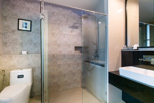 Un baño moderno con ducha de vidrio, inodoro blanco y encimera negra con lavamanos.