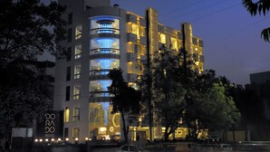 A modern hotel with multiple floors, large windows, and illuminated signage.