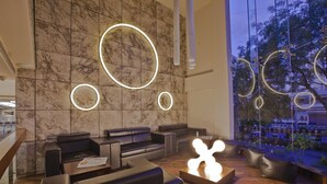 A modern lounge area with leather seating, a wooden coffee table, and illuminated wall art.