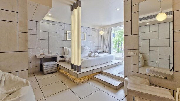A modern bedroom with a large bed, bedside tables, a vanity, and a walk-in closet.