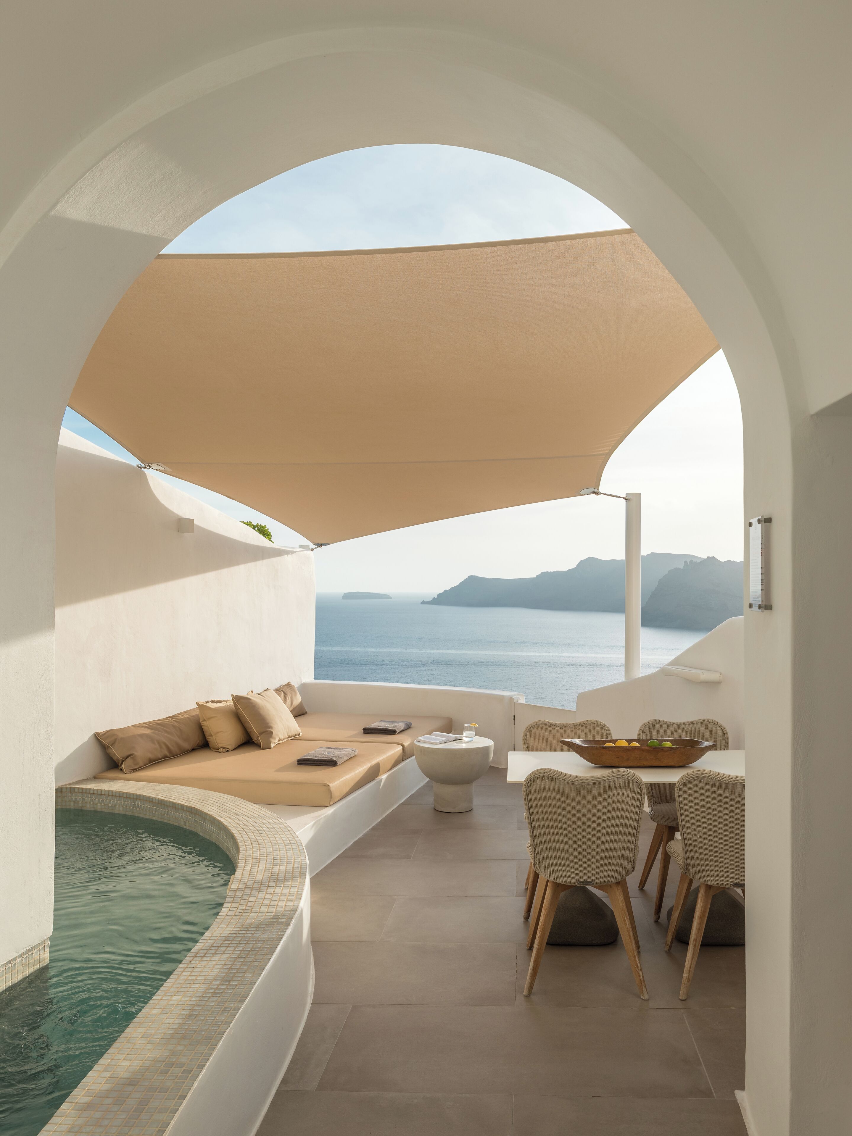 Terraza soleada con piscina, zona de estar y comedor con vistas al mar.