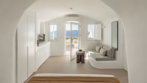 Un interior moderno y blanco con techo curvo, un sofá, una mesita y vistas al exterior.