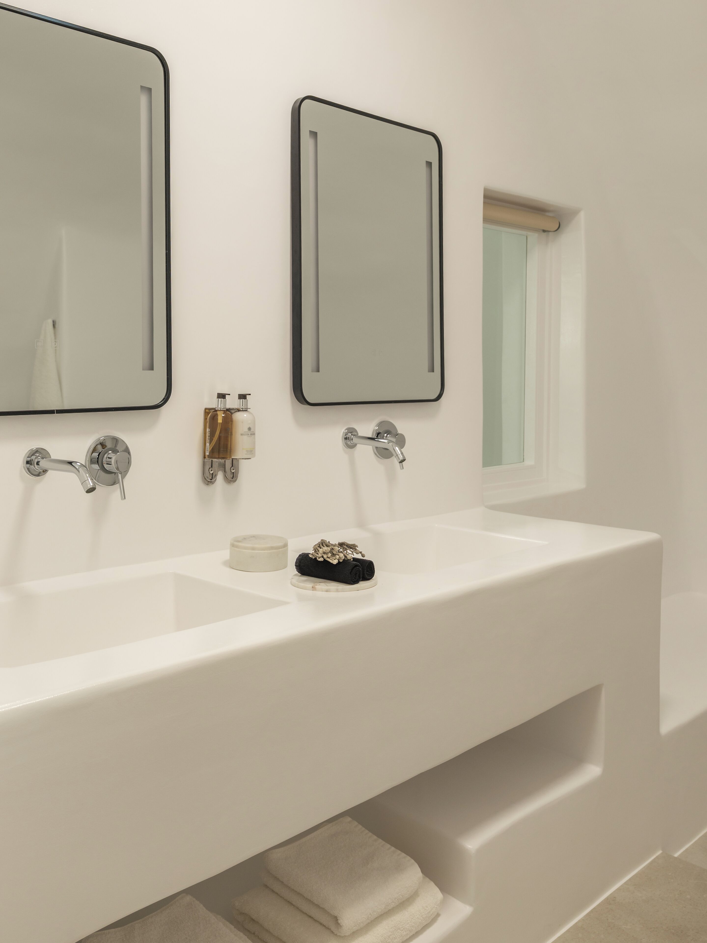 A modern bathroom with two sinks, a large mirror, and a window.