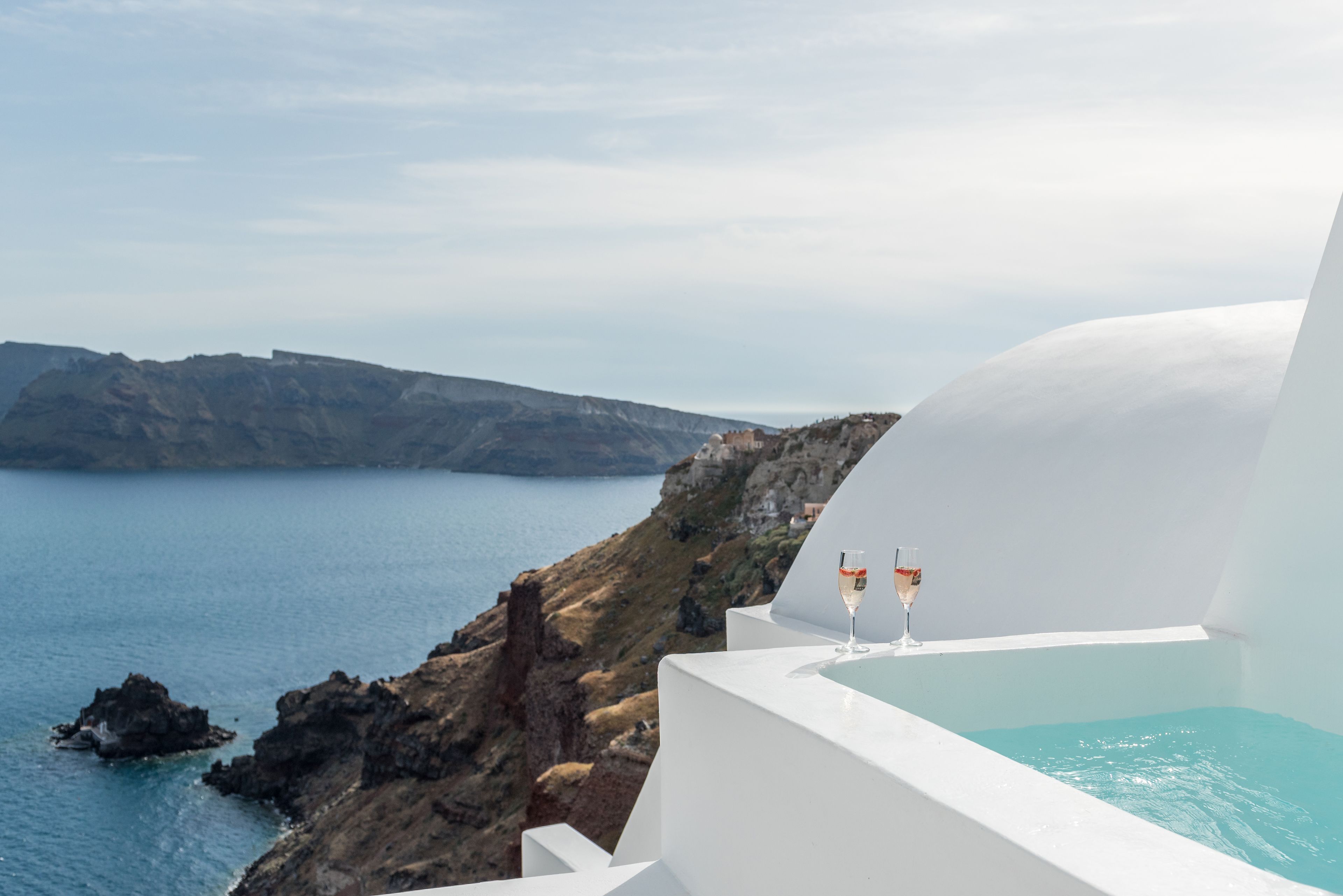 Una piscina infinita blanca con vistas despejadas al mar y a la costa rocosa.