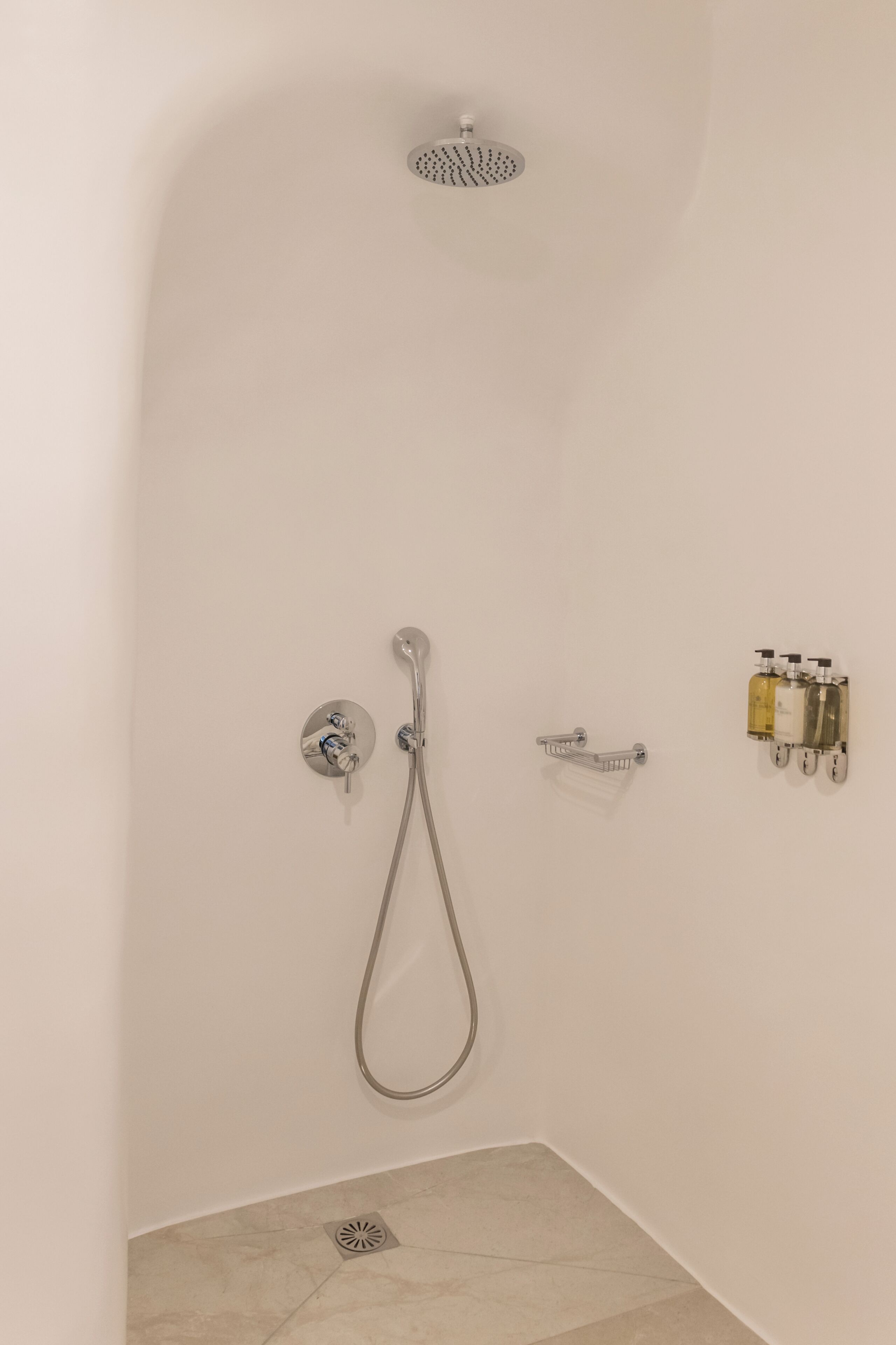 Une douche équipée d’un pommeau de douche à main, d’un robinet mural et d’un flexible de douche à main.