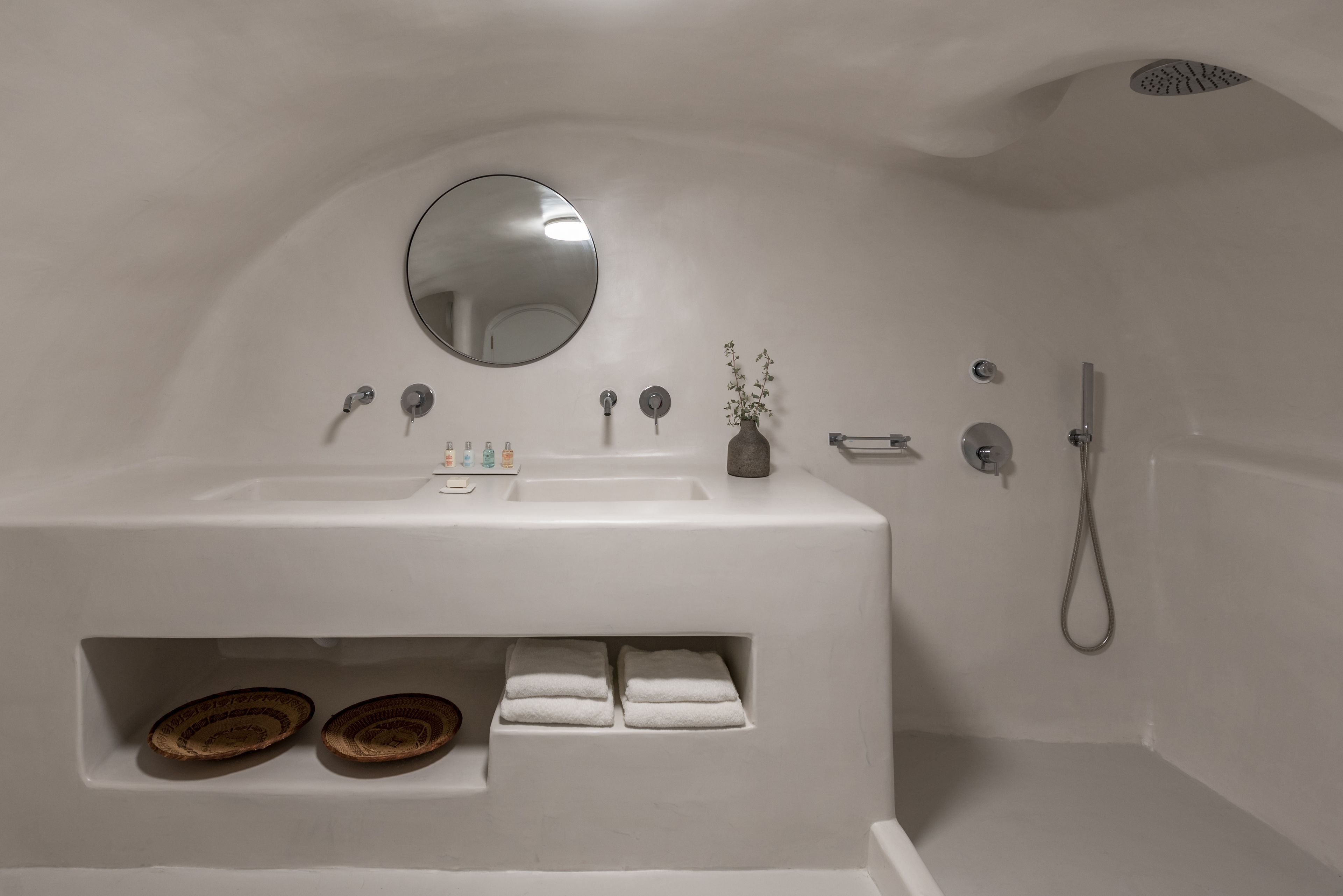 A modern bathroom with a large bathtub, a round mirror, and a shower.