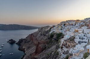 Un pueblo costero con edificios blancos, acantilados escarpados y barcos en el agua.