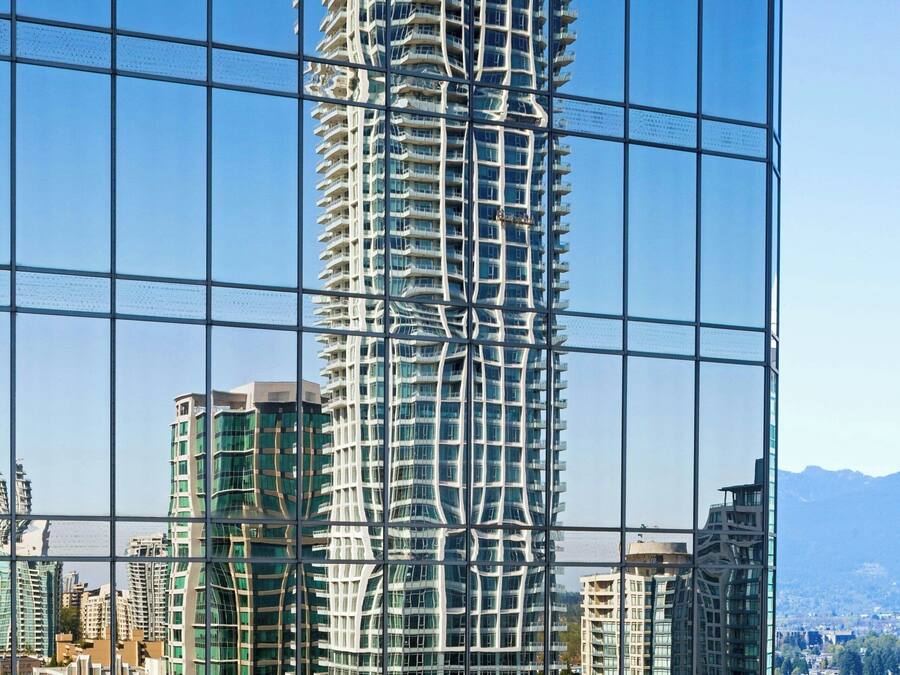 Un edificio moderno de gran altura con una fachada curva distintiva, rodeado de otros edificios y un cielo despejado.