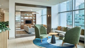 Un moderno vestíbulo de hotel con área de estar, televisor y vista de la ciudad.