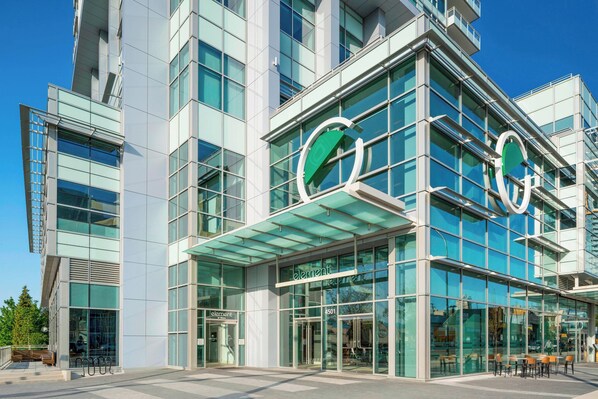 A modern building with a glass facade and a prominent green logo.