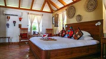 A bedroom with a wooden bed, a chair, a small table, and a wall-mounted air conditioner.