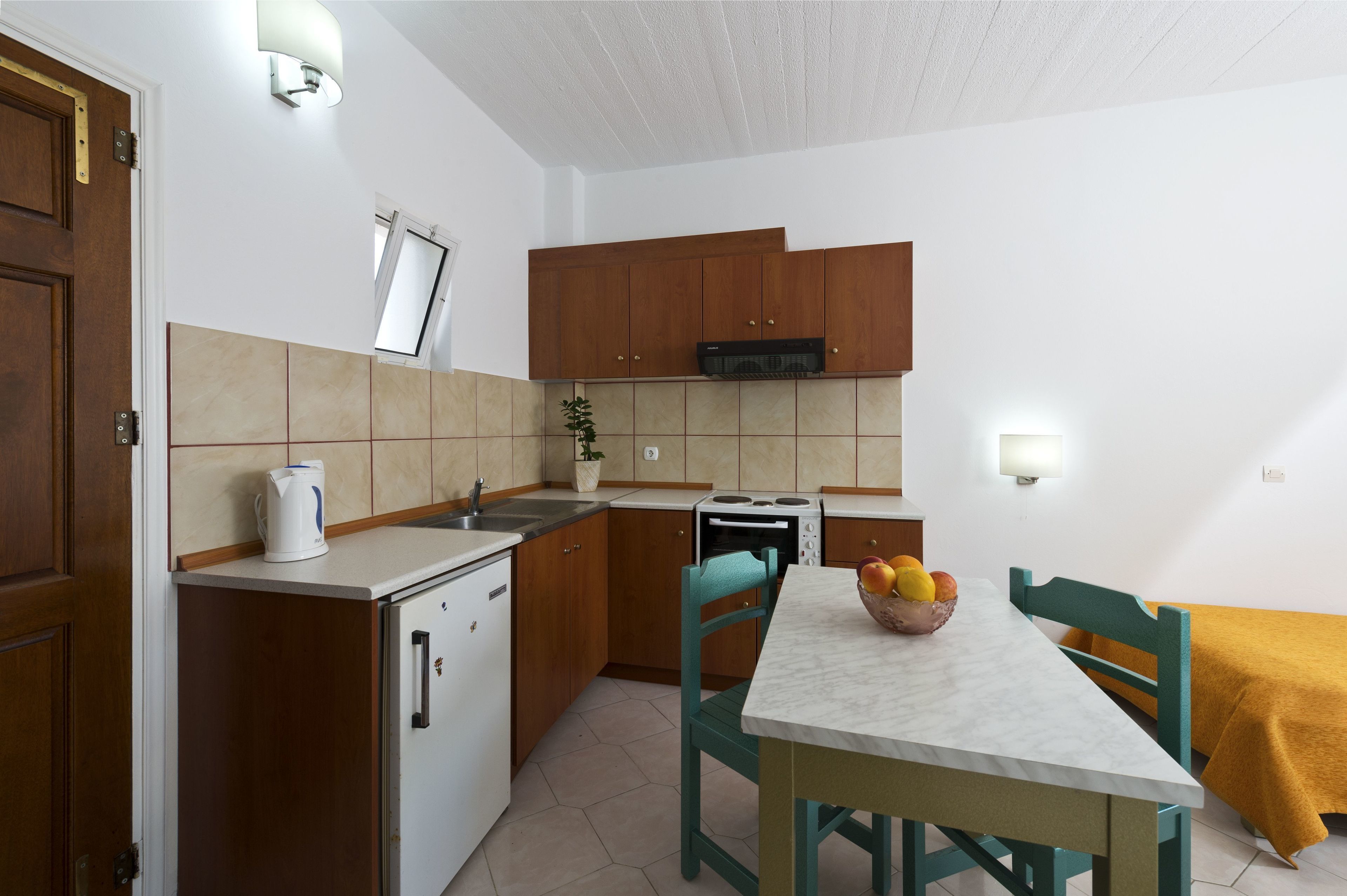 Una cocina compacta con armarios de madera, microondas integrado y un lavamanos pequeño.