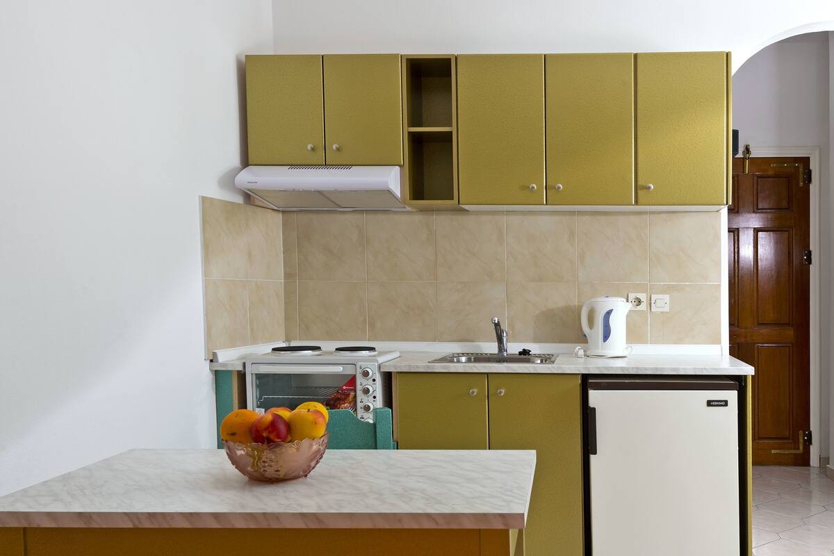 Eine kleine Küche mit eingebautem Ofen, Spüle und kleinem Kühlschrank.