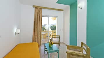 Una habitación con cama, una mesa con un jarrón de flores, una silla y vistas al exterior a través de una puerta corrediza.