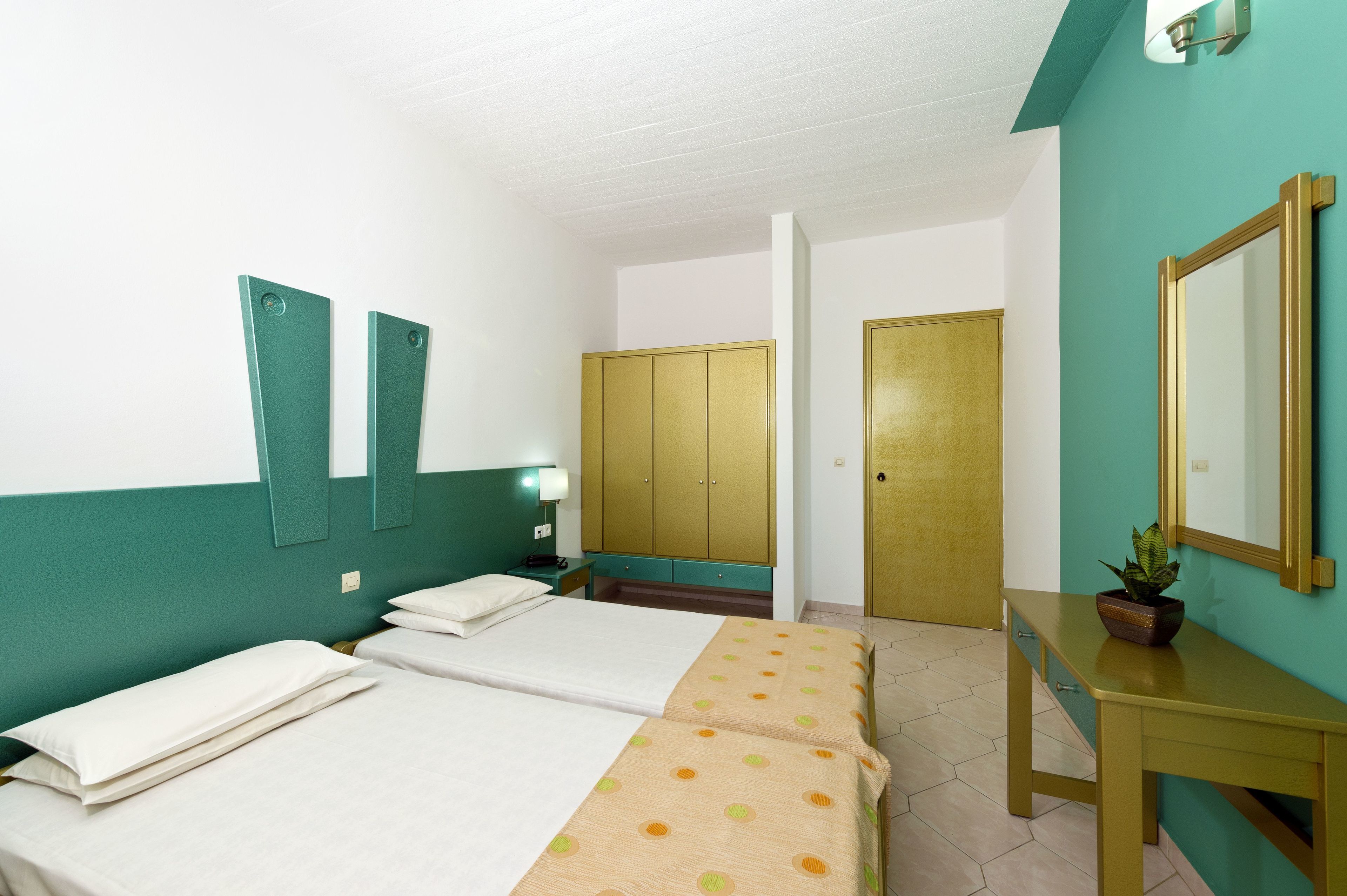 Une chambre d’hôtel avec deux lits, un bureau, un miroir et une armoire.
