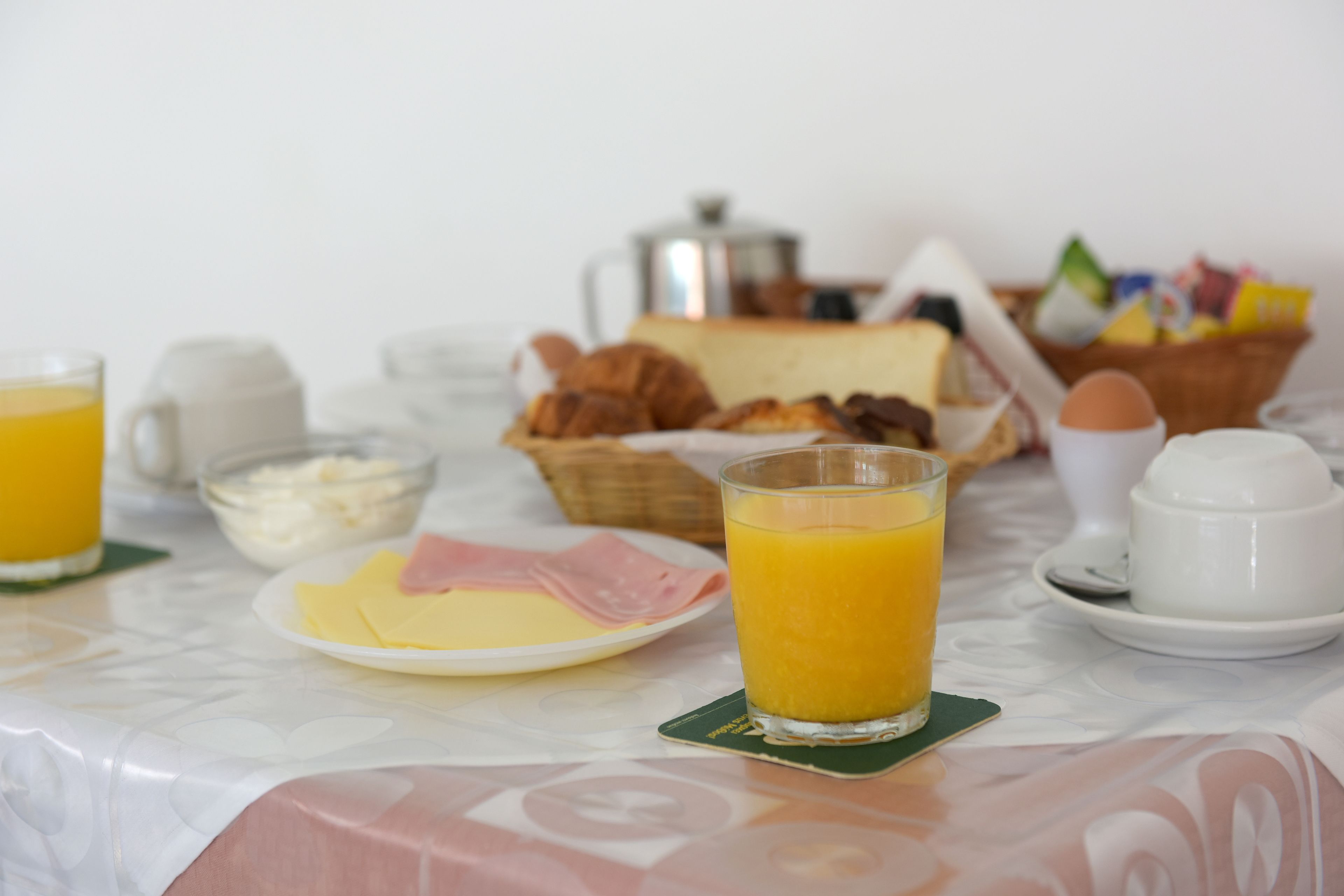 A breakfast table with plates of food, a glass of orange juice, and a coffee pot.