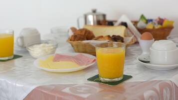 A breakfast table with plates of food, a glass of orange juice, and a coffee pot.