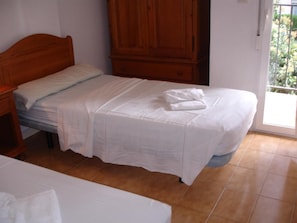 A single bed with white bedding, a wooden headboard, and a wooden wardrobe in a room with tiled flooring. - Rinconada Real Bungalows (Benidorm)