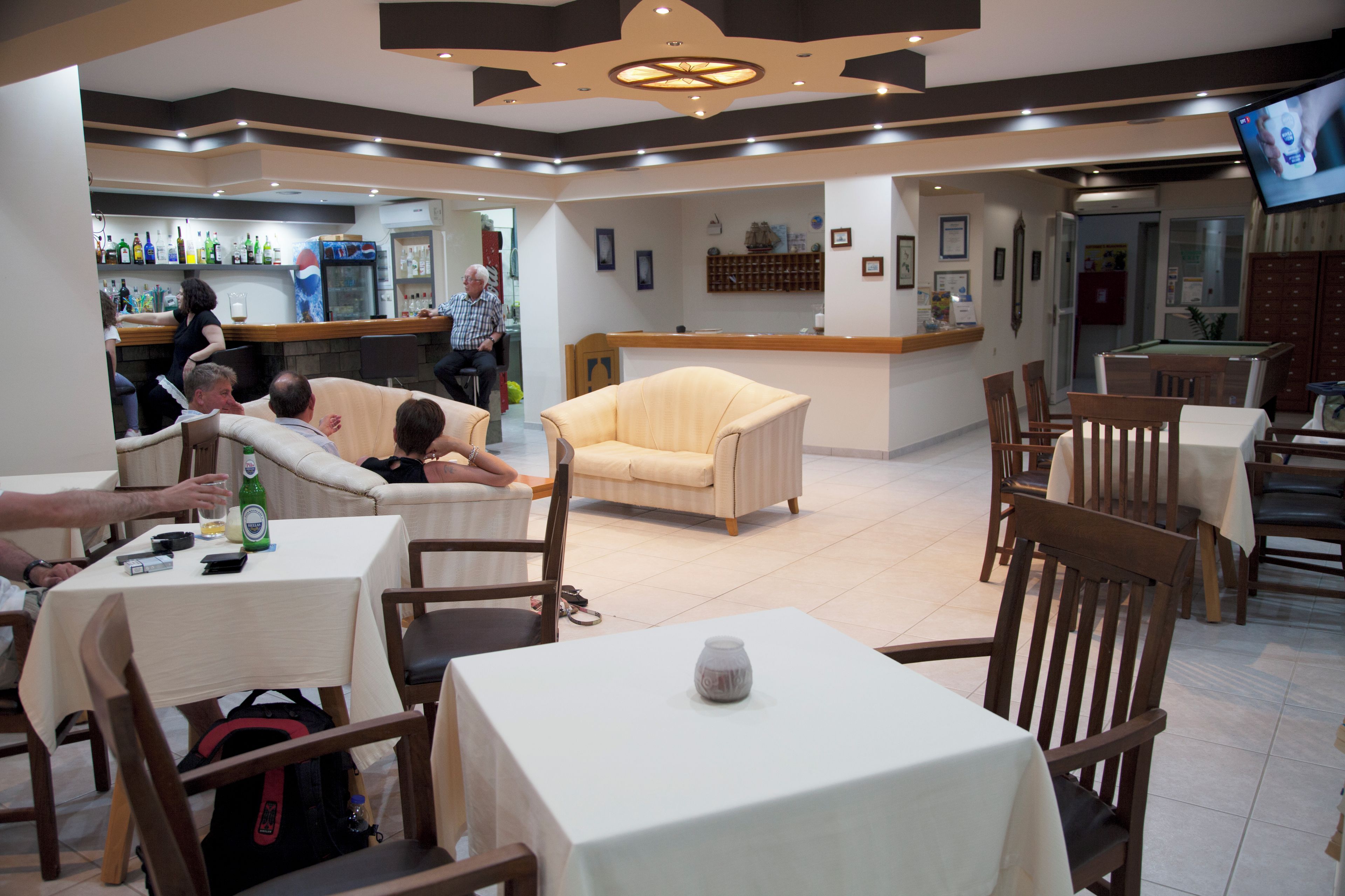 Ein Restaurant mit Tischen, Stühlen, einer Bar und einem Fernseher.