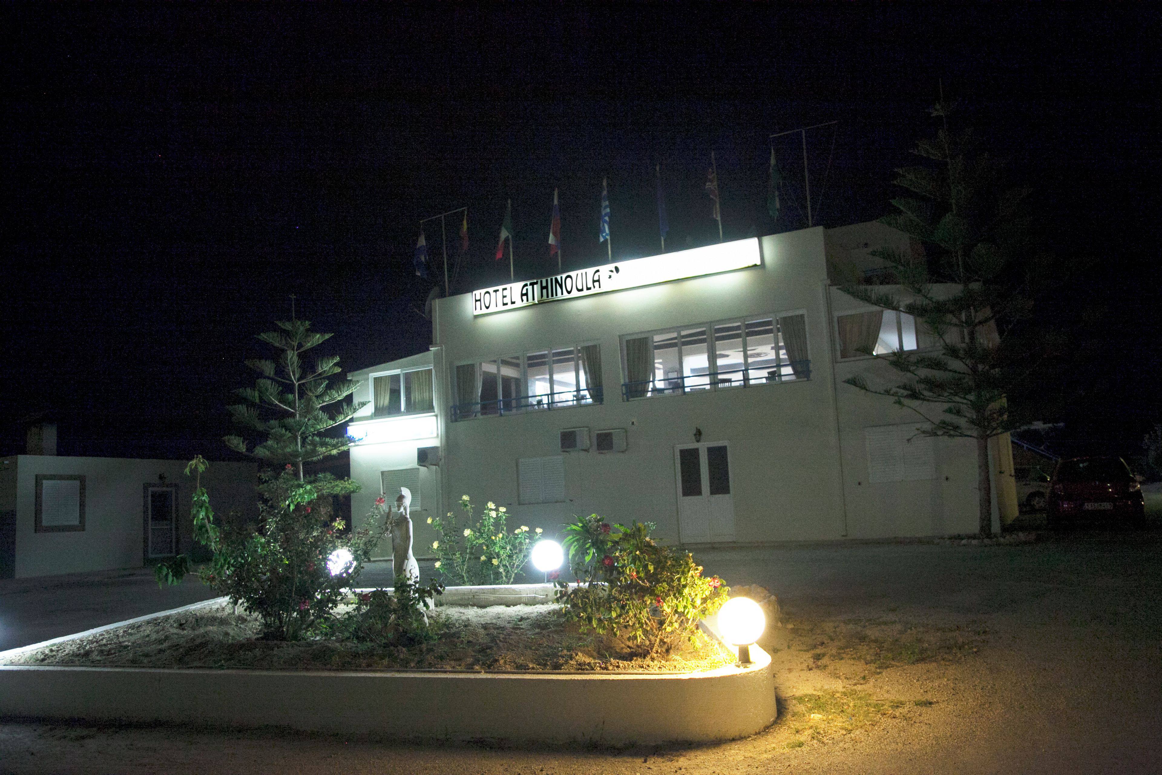 A building with a sign reading 'HOTEL ATHINOULA' at night.
