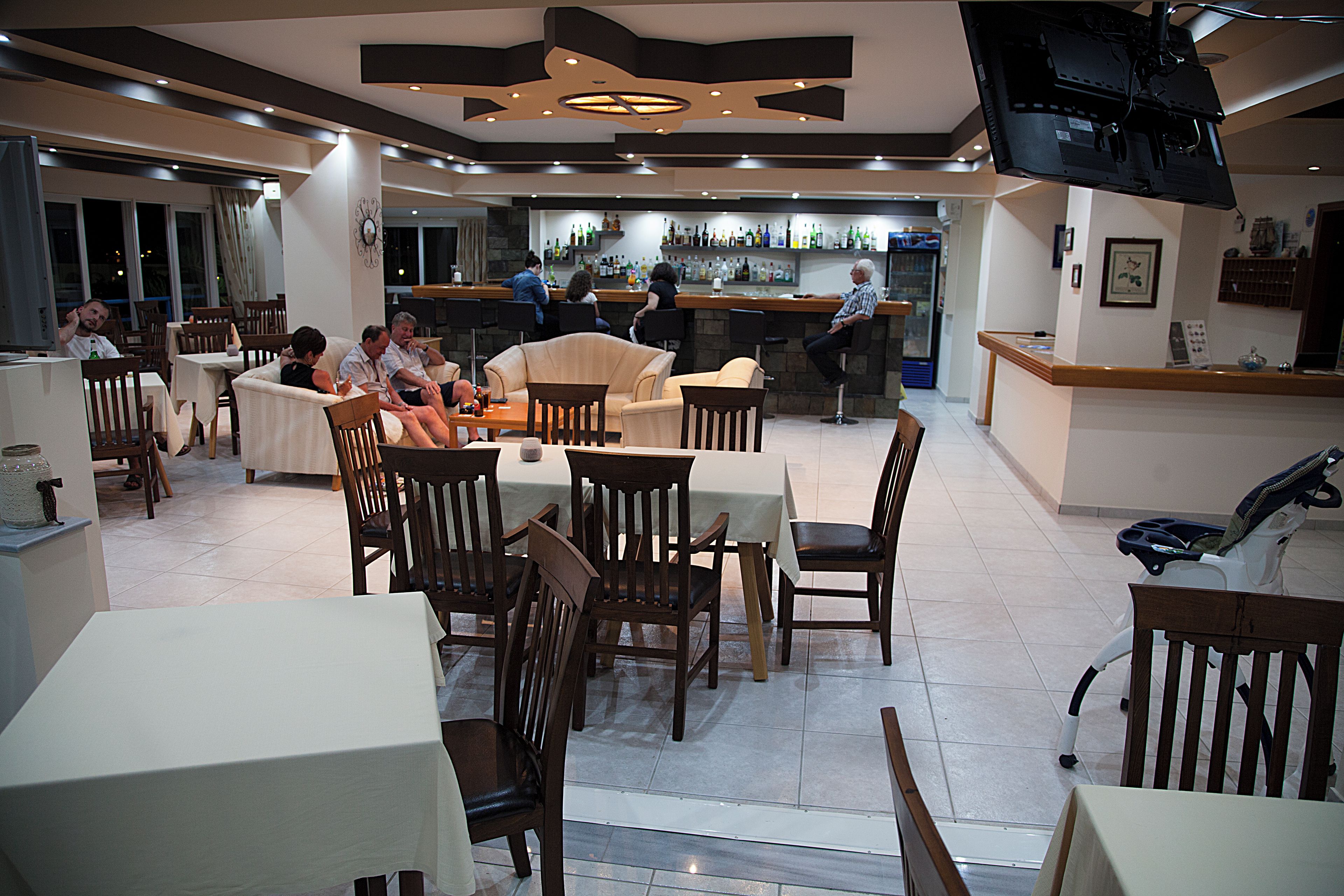 Um restaurante com várias áreas de refeição, incluindo mesas e cadeiras, e um bar ao fundo.
