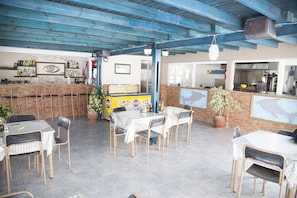 Un restaurante con terraza, una zona de bar y una cocina visible a través del espacio abierto.
