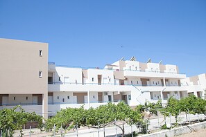 A multi-story residential building with balconies and a clear sky. - Athinoula (Kos)