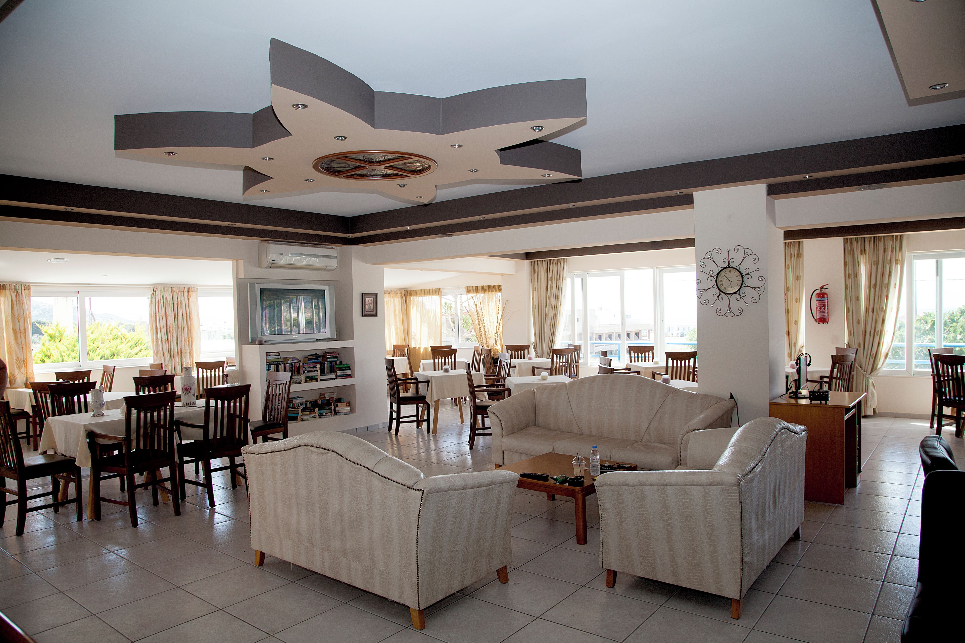 A spacious living area with a large sofa, dining tables, and chairs.