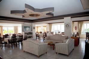 A spacious living area with a large sofa, dining tables, and chairs. - Athinoula (Kos)