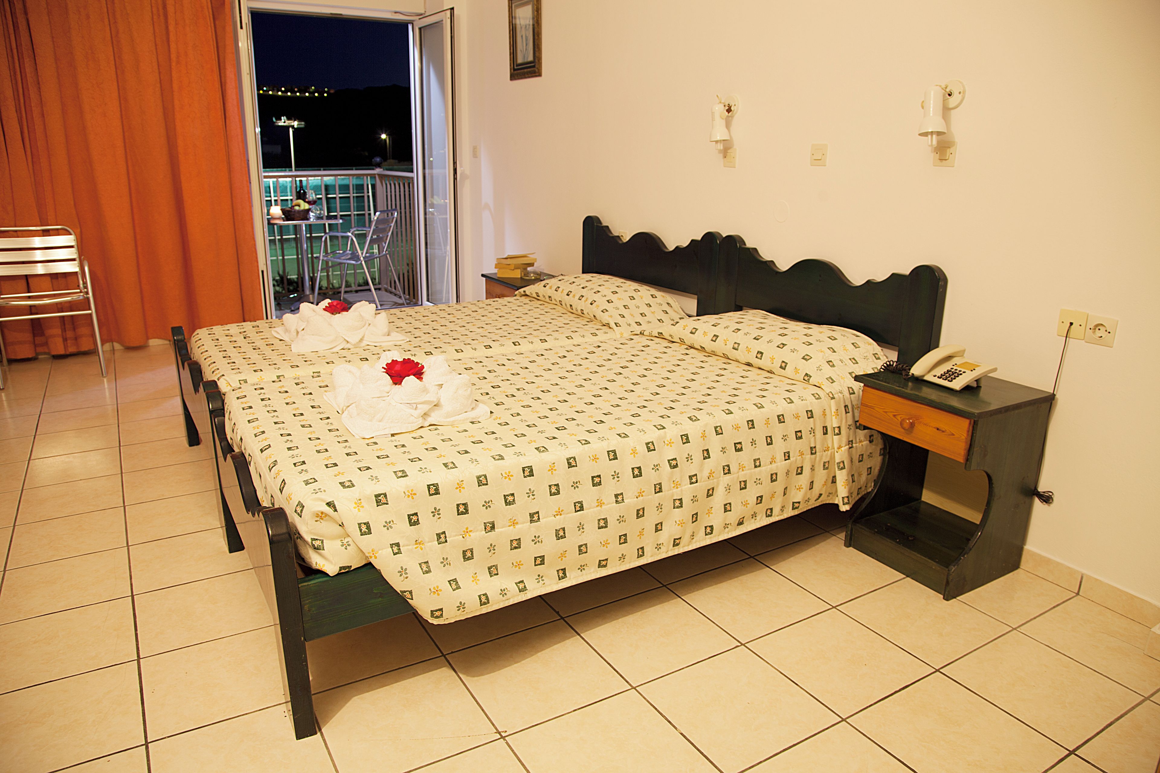 A hotel room with a bed, a nightstand, a chair, and a view of the outside.