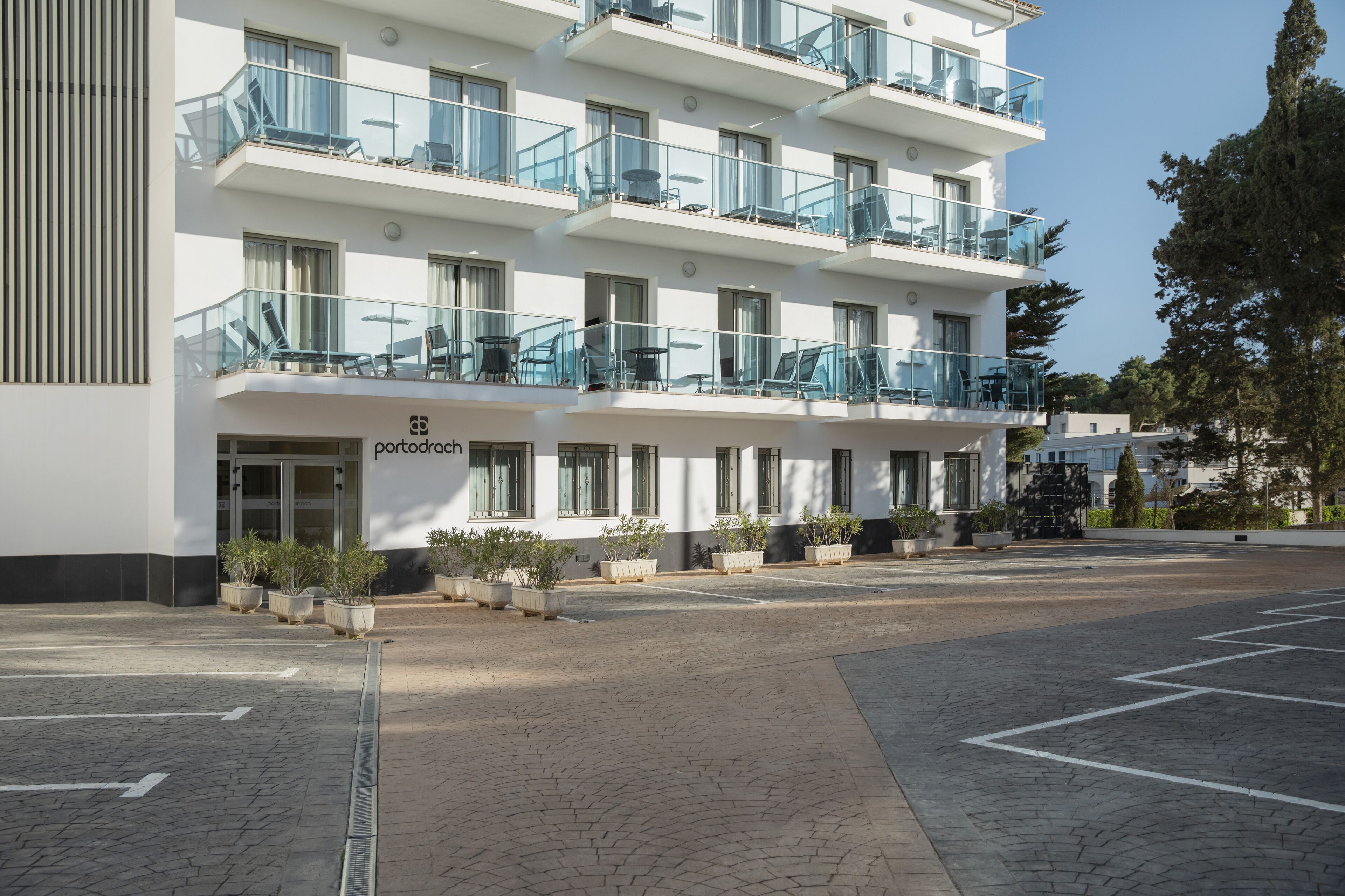 A multi-story hotel with balconies, outdoor seating, and potted plants.