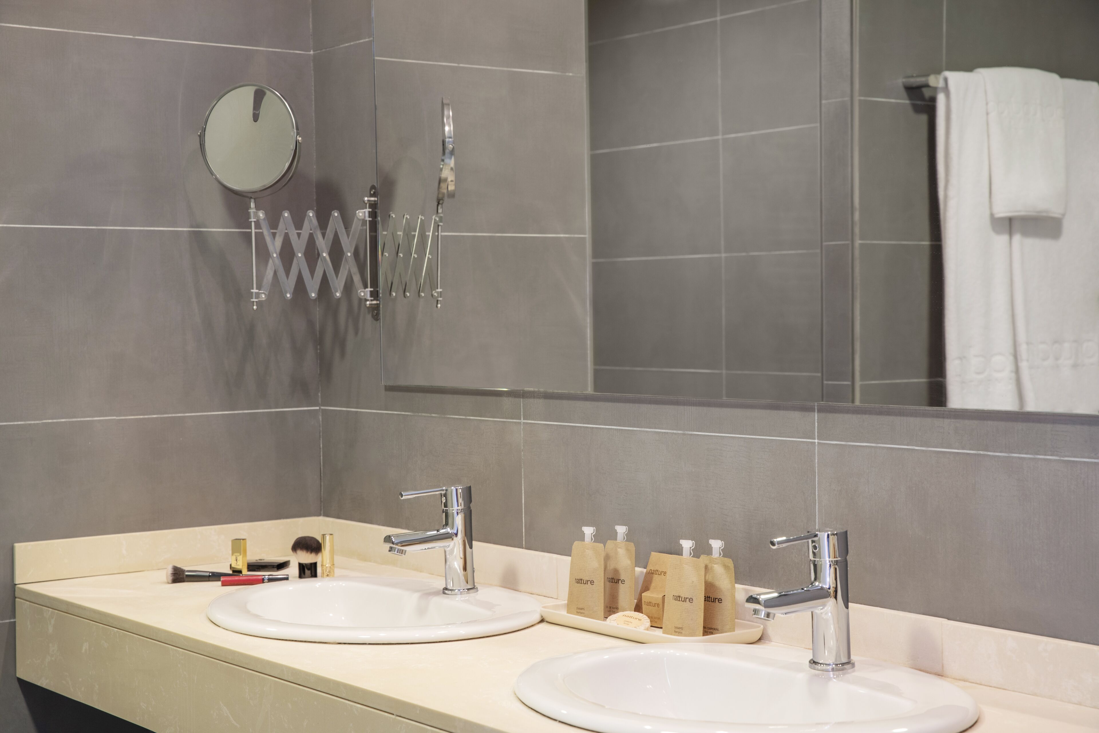 A bathroom with two sinks, a mirror, and a towel rack.