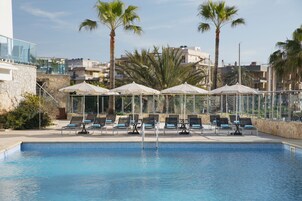 Una piscina al aire libre, tumbonas