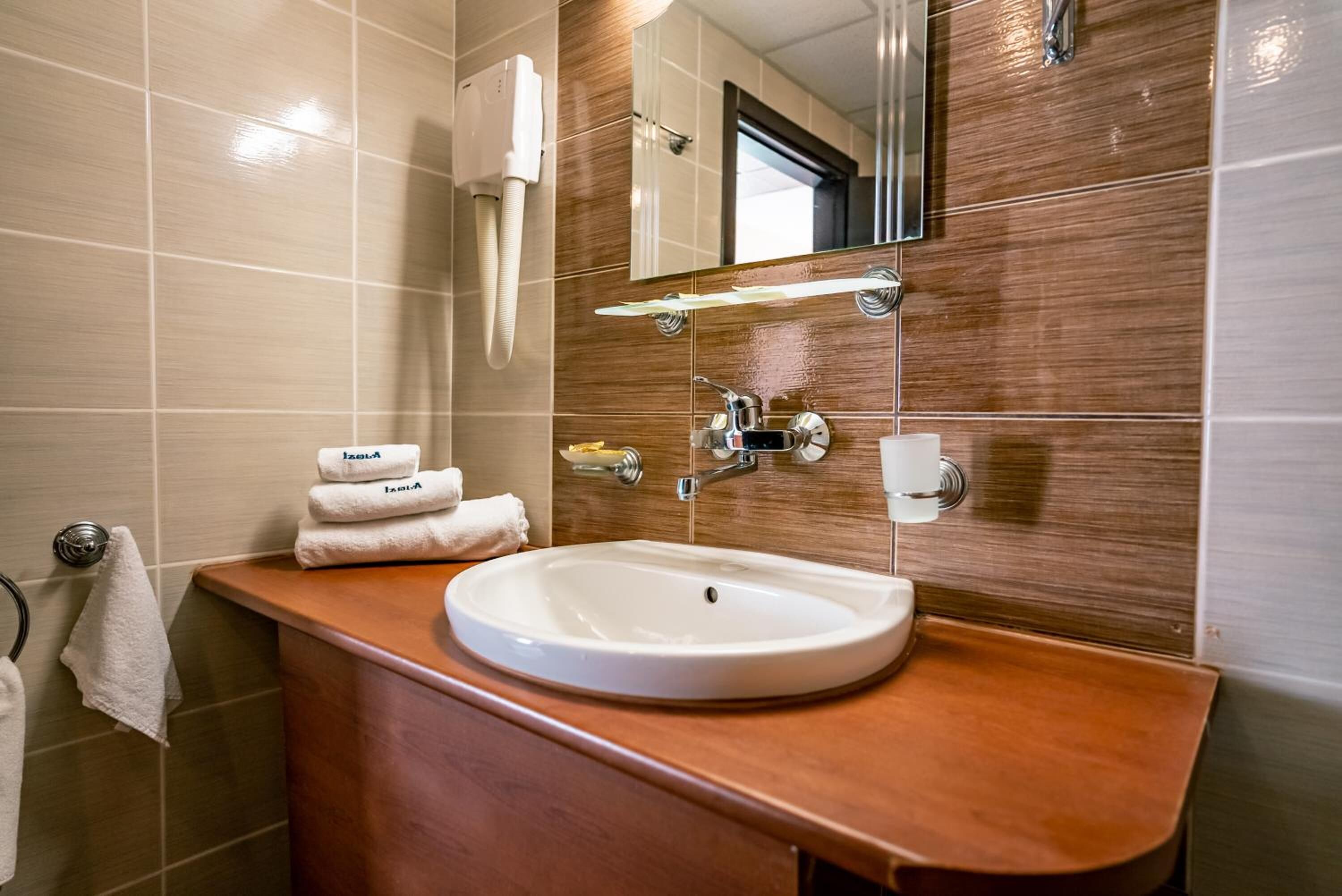 Ein Badezimmer mit Waschbecken, Spiegel, Handtuchhalter und Handtuchspender.