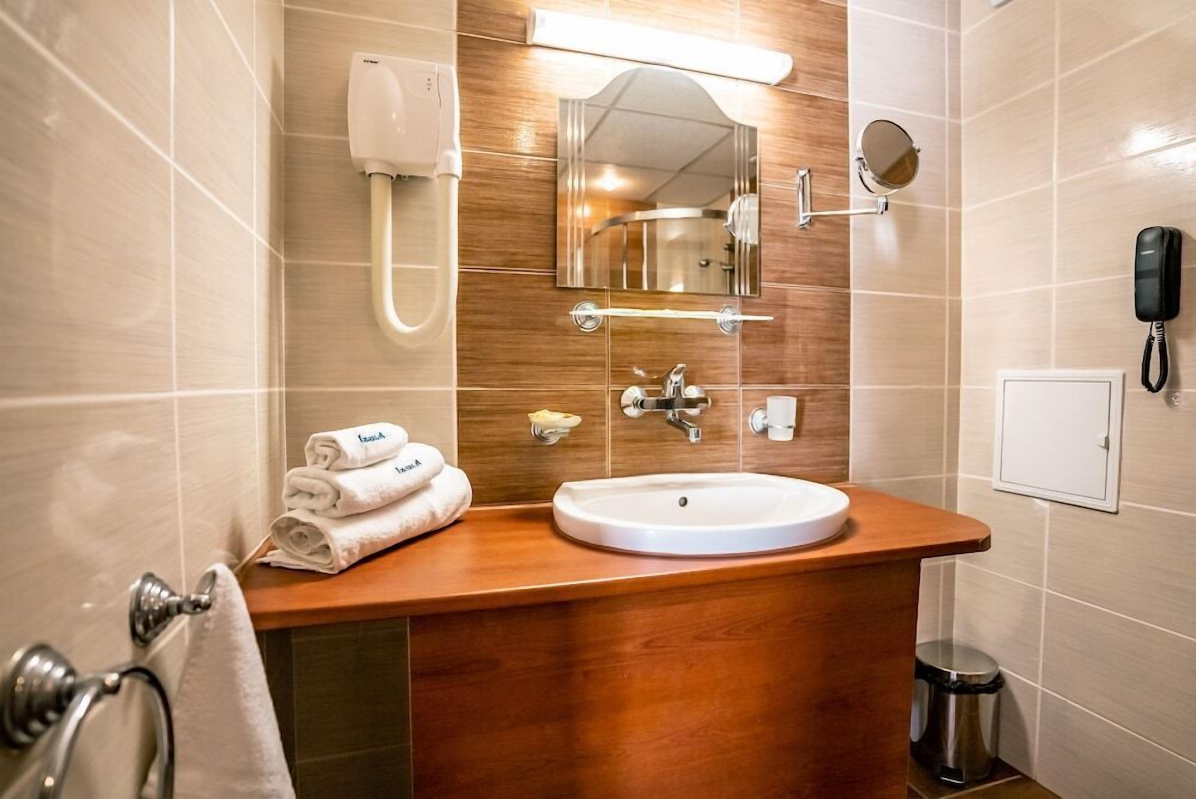 A bathroom with a sink, mirror, towel rack, and a trash bin.
