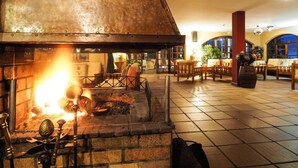 Ein Restaurant mit Kamin aus Backstein, Holzmöbeln und Fliesenboden.